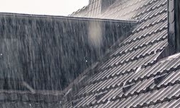 This image depicts a rooftop during a heavy rainstorm, illustrating potential leaking issues. The photograph enhances the article about dealing with roof leaks after a Katy storm.